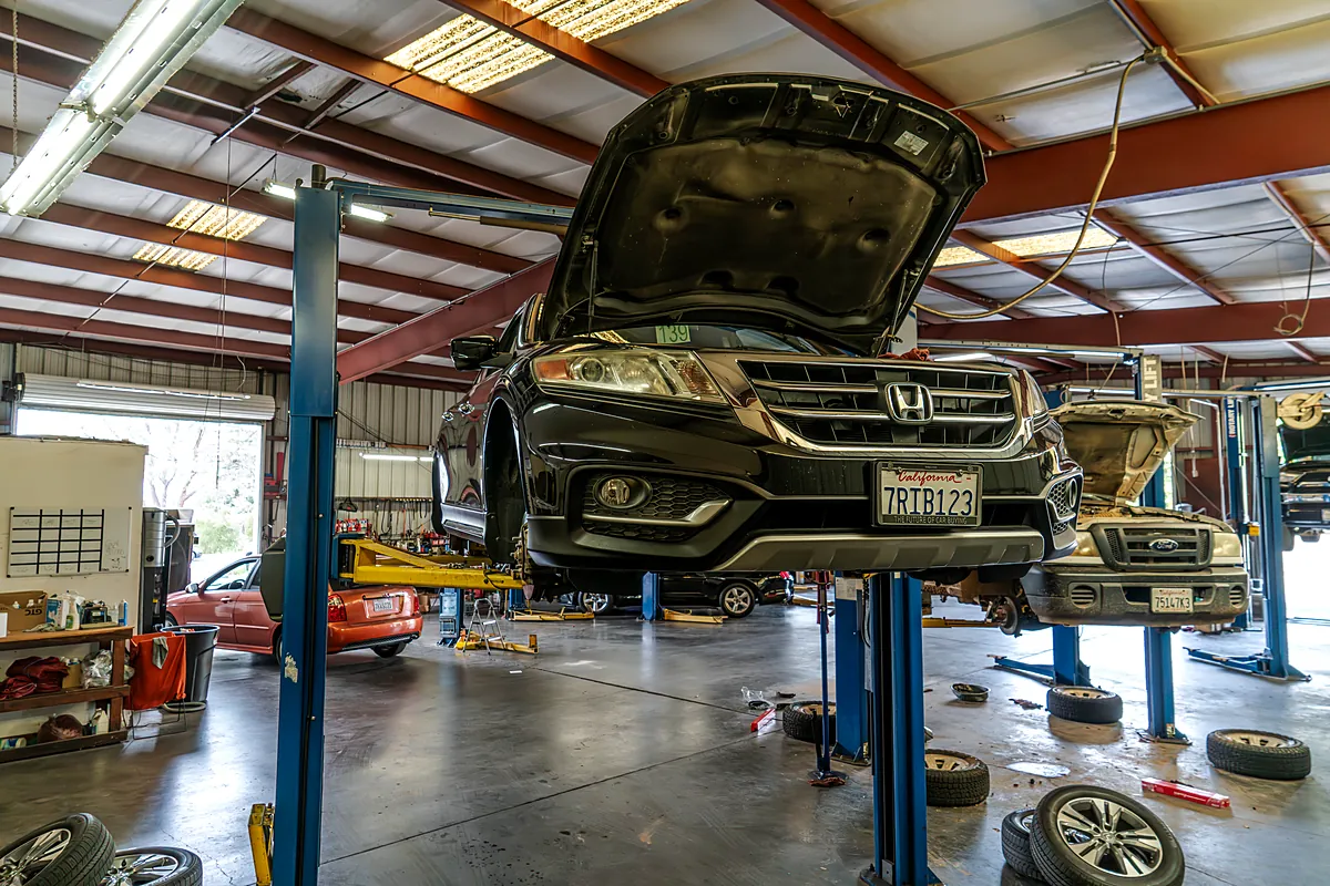 Full shop floor, SUV up on a two-post lift