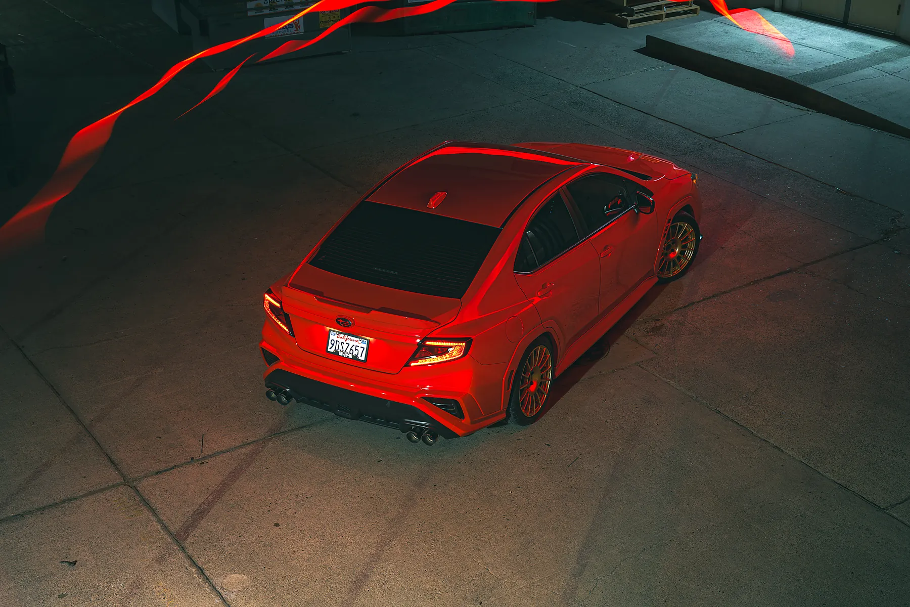Red WRX at night, ringed by light-painted streaks