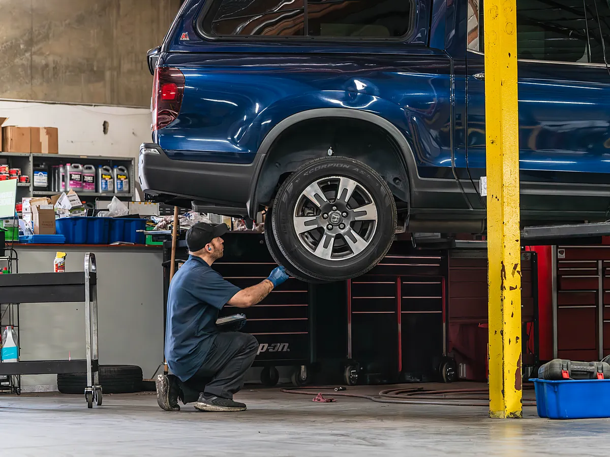 Tech crouched under a truck on the lift